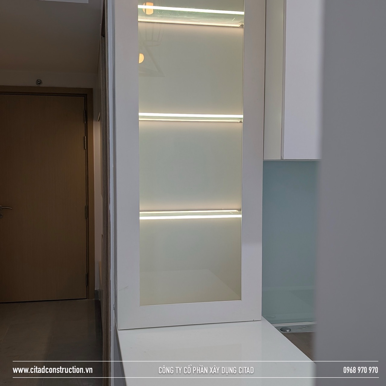 Hệ tủ trưng bày gỗ MDF phủ kính trắng có đèn LED, thi công tinh tế bởi CITAD trong căn hộ hiện đại tại Long Xuyên